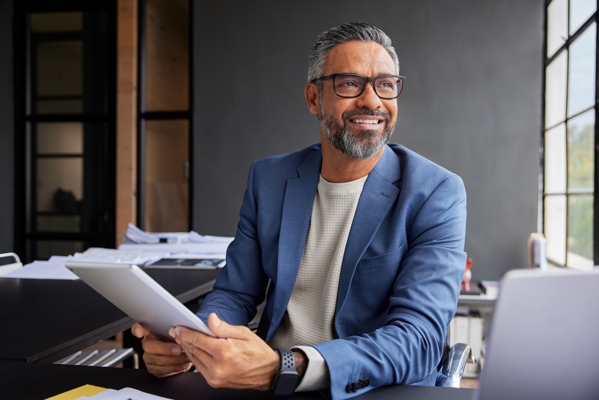 Hombre de negocios sonriente usando tableta mientras mira por la ventana